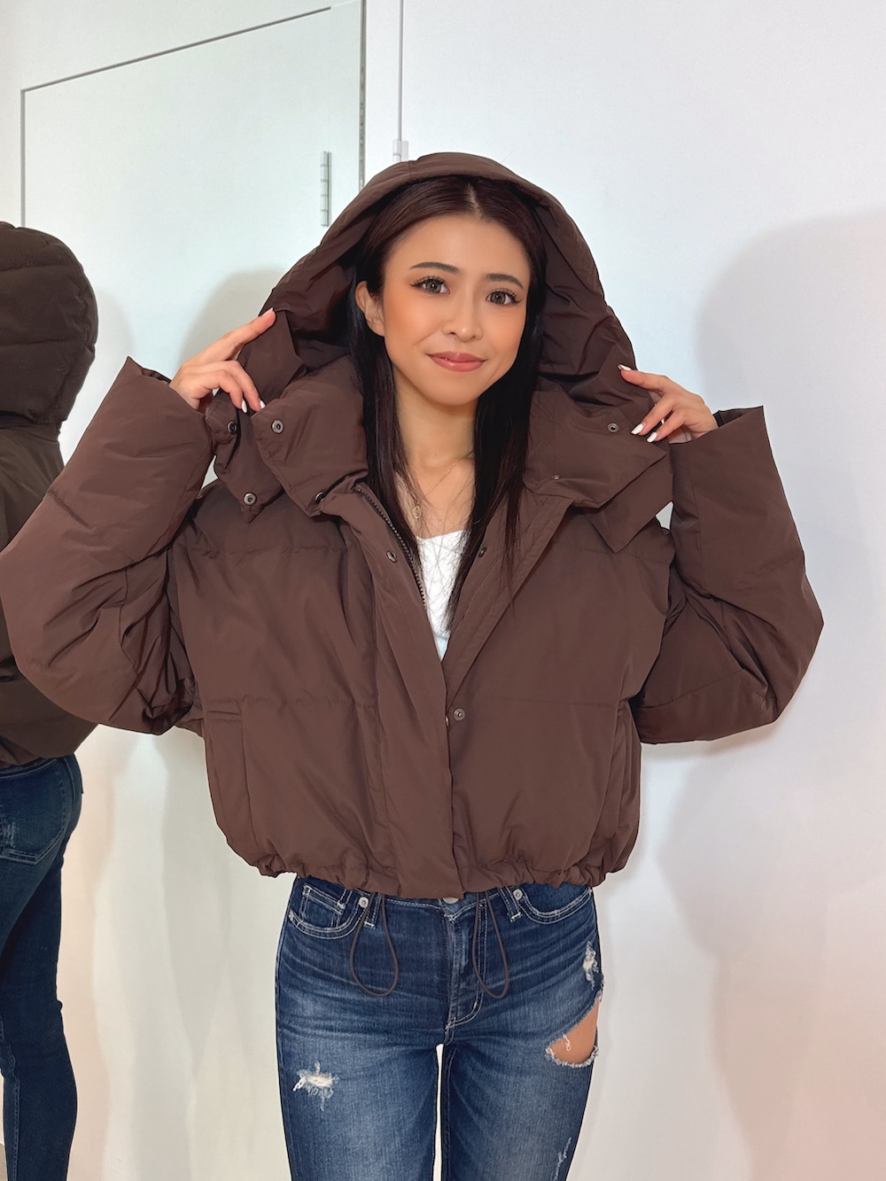 ホワイト系のTシャツ/カットソー、ブラウン系のダウンジャケット/コート、ブルー系のデニムパンツを着用したレディースの秋コーディネートの6枚目の写真