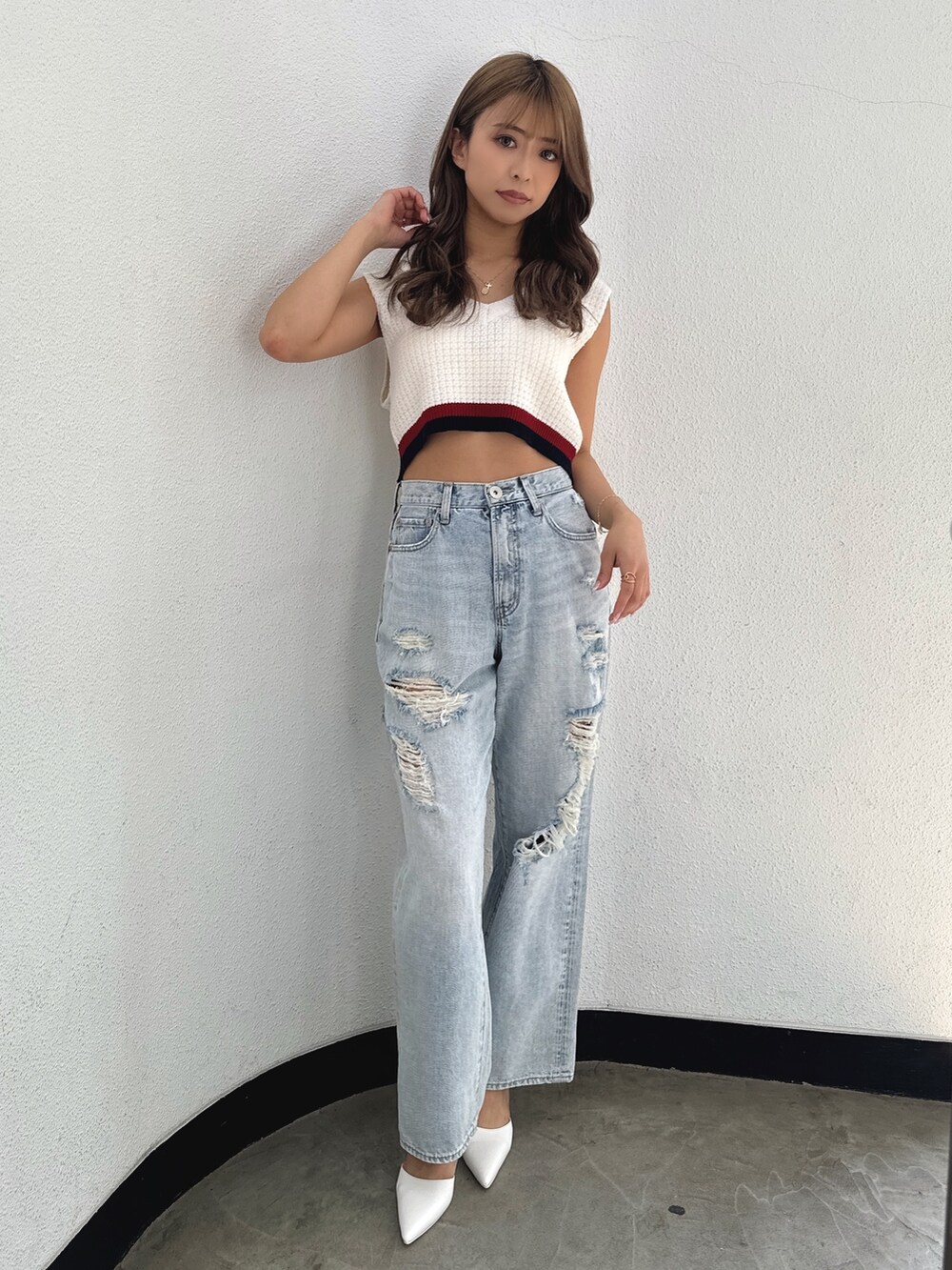 ホワイト系のニット/セーター、ブルー系のデニムパンツ、ホワイト系のパンプスを着用したレディースの春コーディネートの2枚目の写真