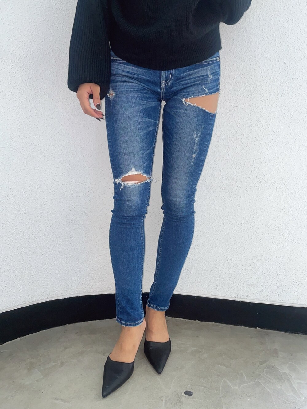 ブラック系のニット/セーター、ブルー系のデニムパンツ、ブラック系のパンプスを着用したレディースの秋コーディネートの5枚目の写真