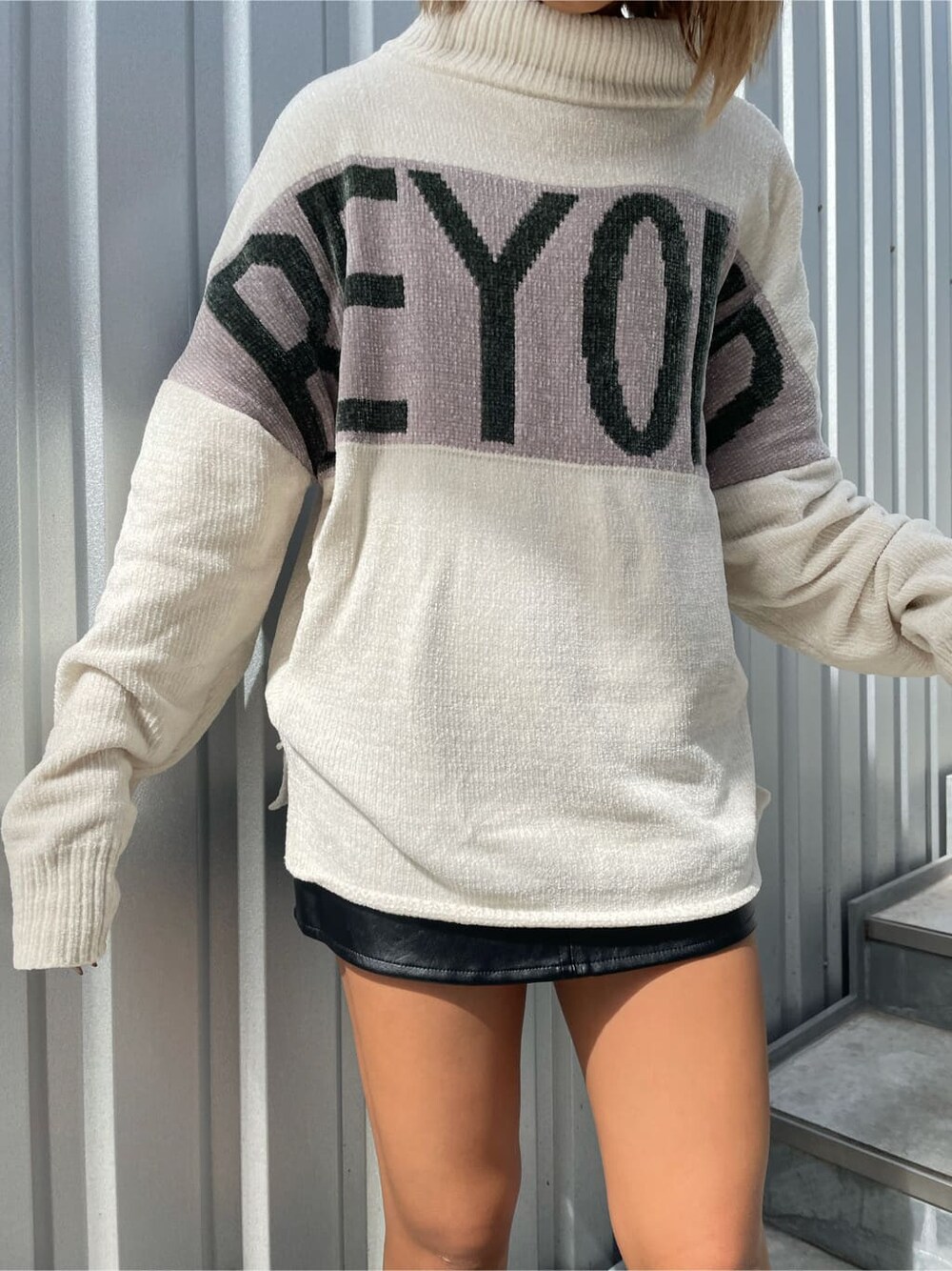 ブラック系のスカート、ブラック系のブーツ、ホワイト系のニット/セーターを着用したレディースの秋コーディネートの4枚目の写真