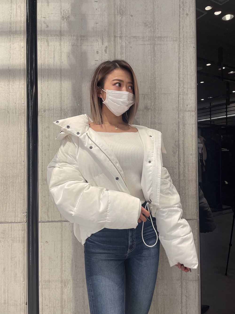 ブルー系のパンツ、ホワイト系のダウンジャケット/コート、ホワイト系のニット/セーターを着用したレディースの冬コーディネートの3枚目の写真