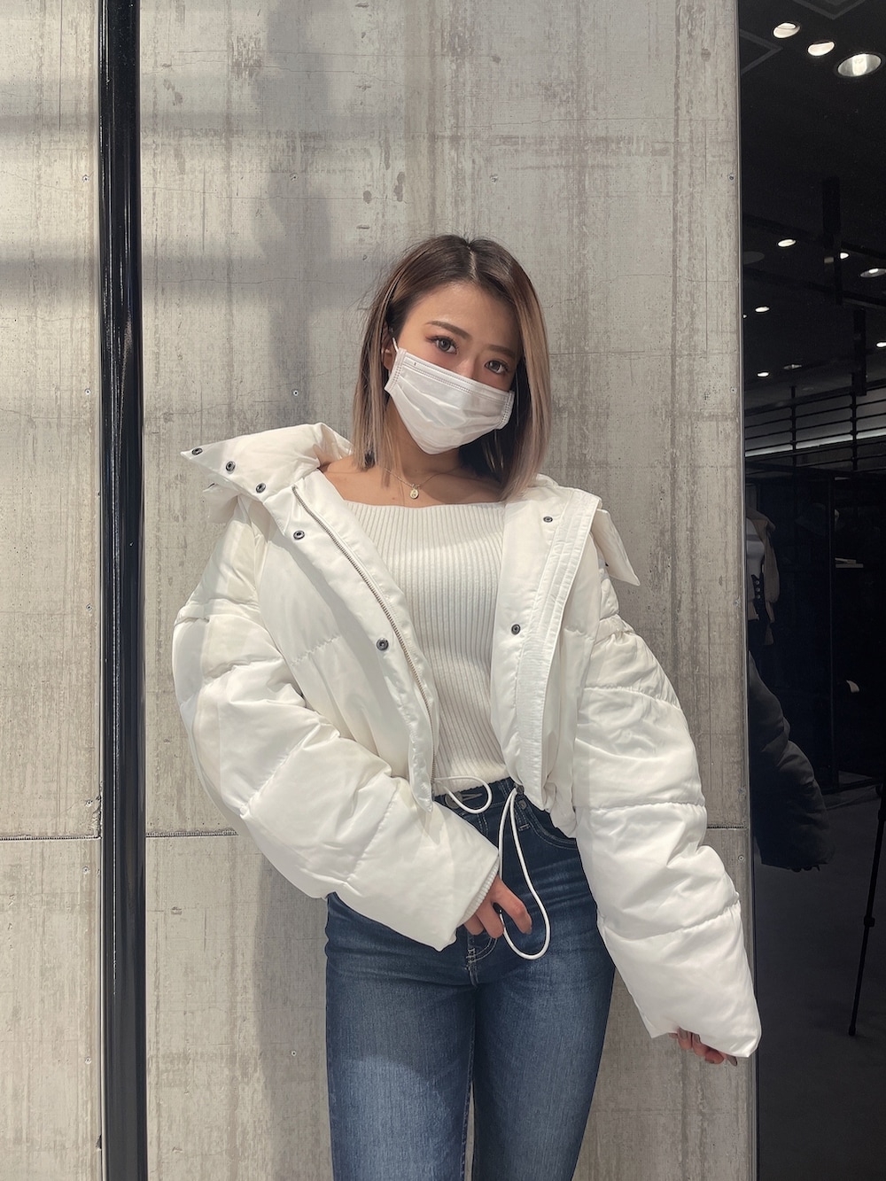 ブルー系のパンツ、ホワイト系のダウンジャケット/コート、ホワイト系のニット/セーターを着用したレディースの冬コーディネートの4枚目の写真