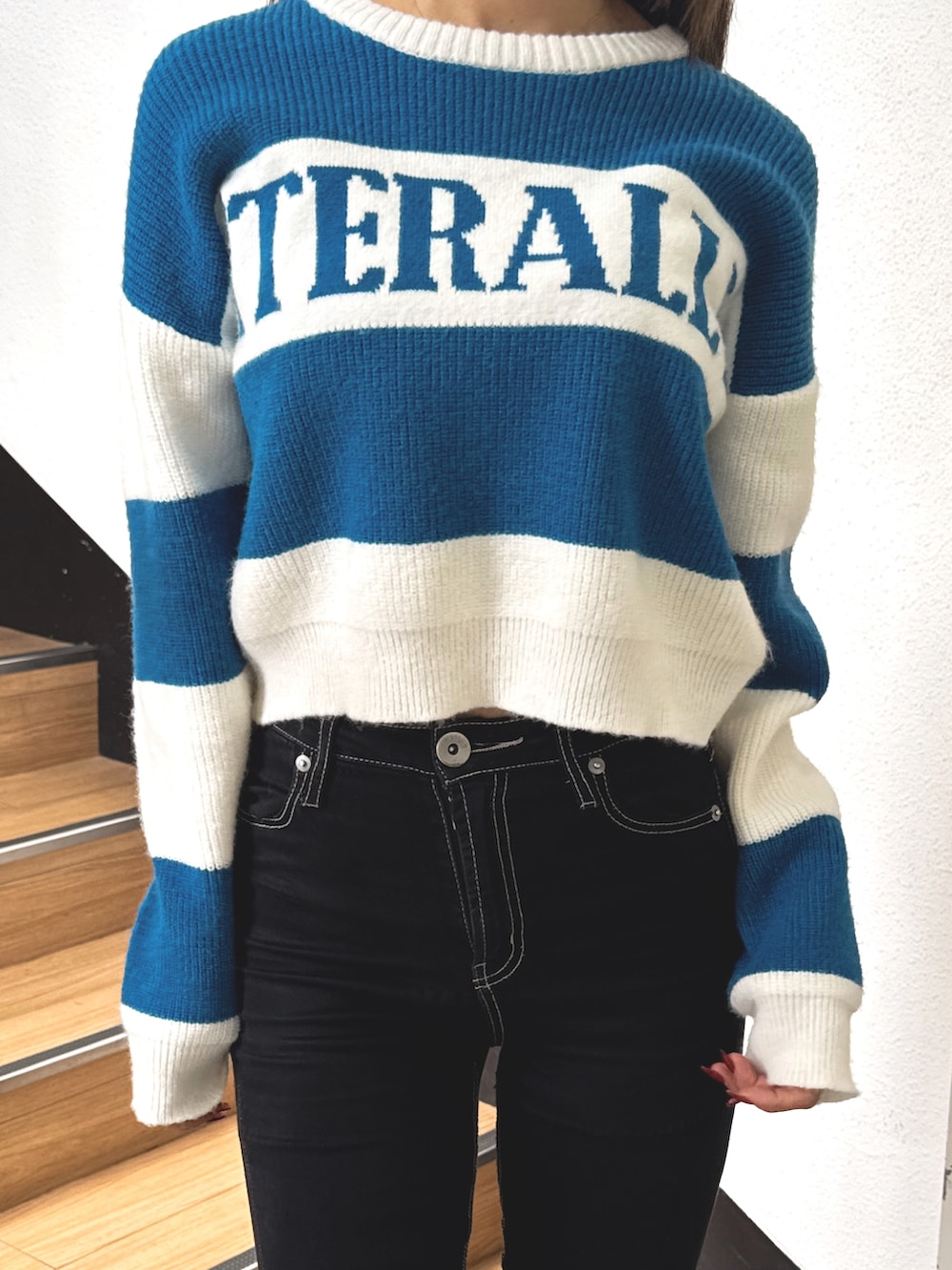 ブルー系のニット/セーター、ブラック系のデニムパンツ、ブラック系のブーツを着用したレディースの秋コーディネートの6枚目の写真
