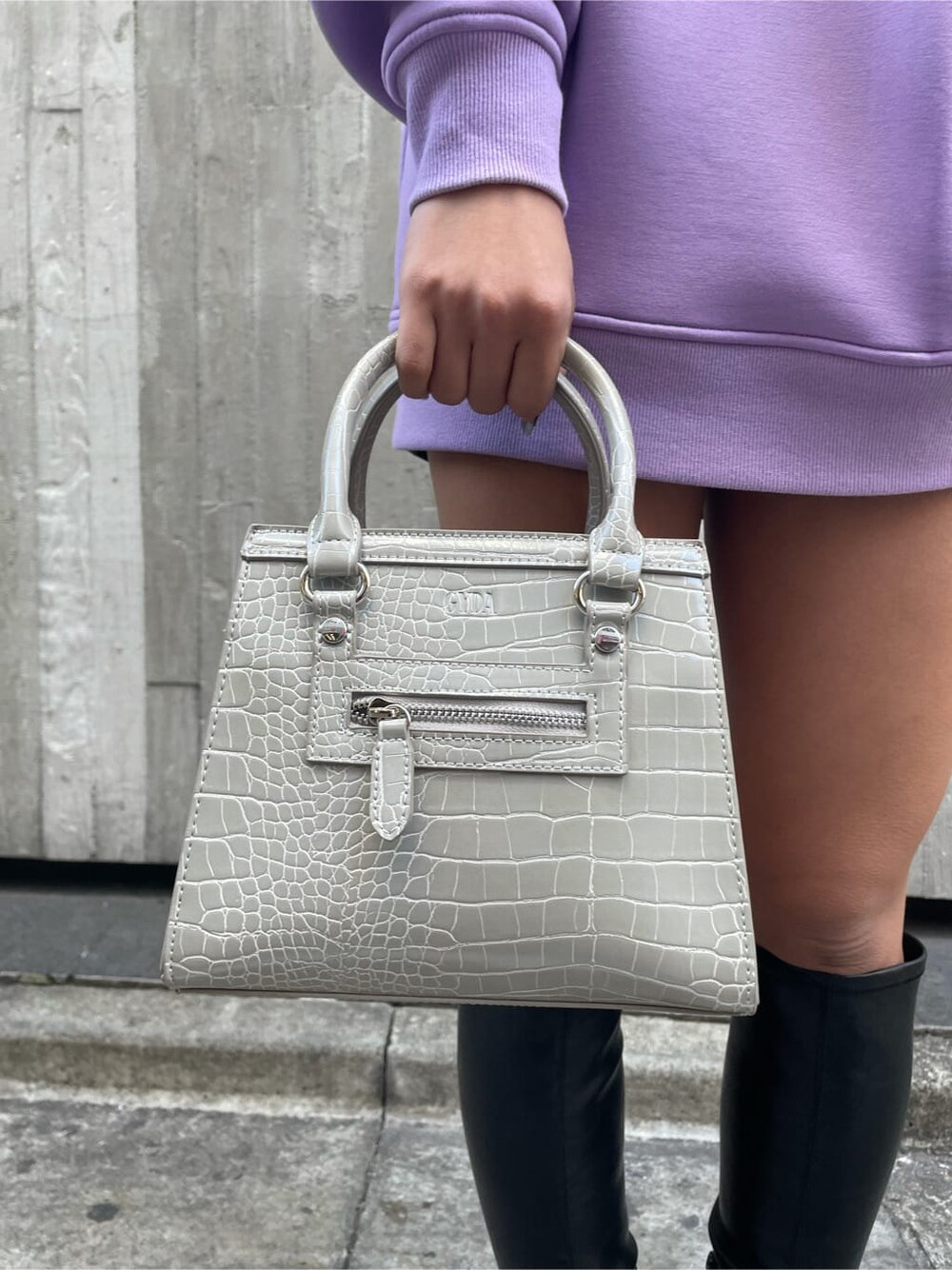 パープル系のTシャツ/カットソー、ブラック系のブーツ、ブラック系のスカートを着用したレディースの冬コーディネートの5枚目の写真