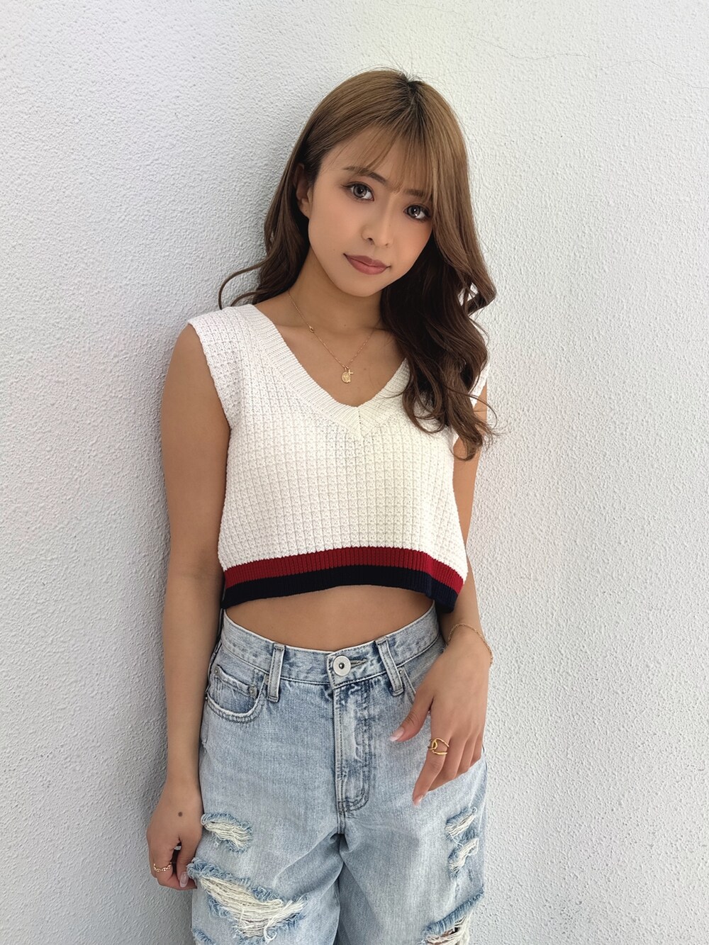 ホワイト系のニット/セーター、ブルー系のデニムパンツ、ホワイト系のパンプスを着用したレディースの春コーディネートの5枚目の写真