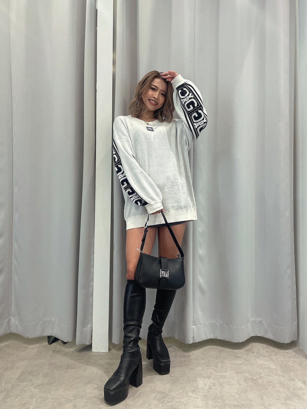 ブラック系のブーツ、ブラック系のハンドバッグ、ホワイト系のニット/セーターを着用したレディースの冬コーディネートの2枚目の写真