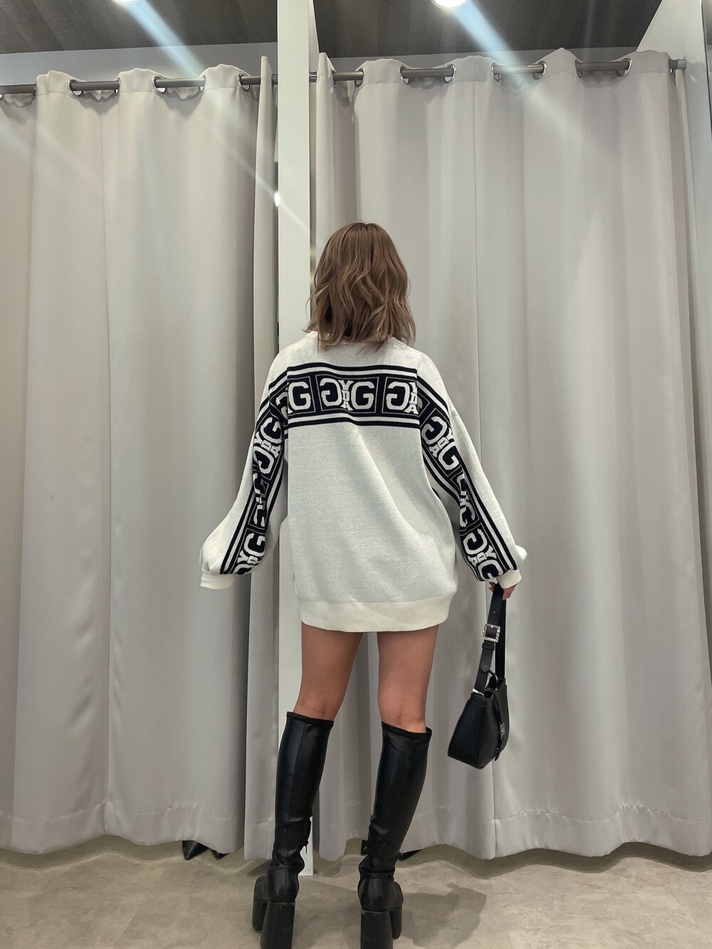 ブラック系のブーツ、ブラック系のハンドバッグ、ホワイト系のニット/セーターを着用したレディースの冬コーディネートの5枚目の写真