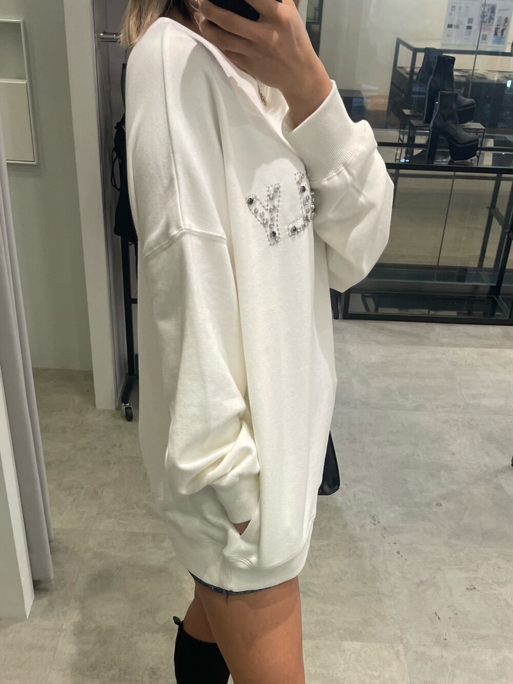 ホワイト系のスウェット、ブルー系のデニムスカート、ブラック系のショルダーバッグを着用したレディースの冬コーディネートの5枚目の写真