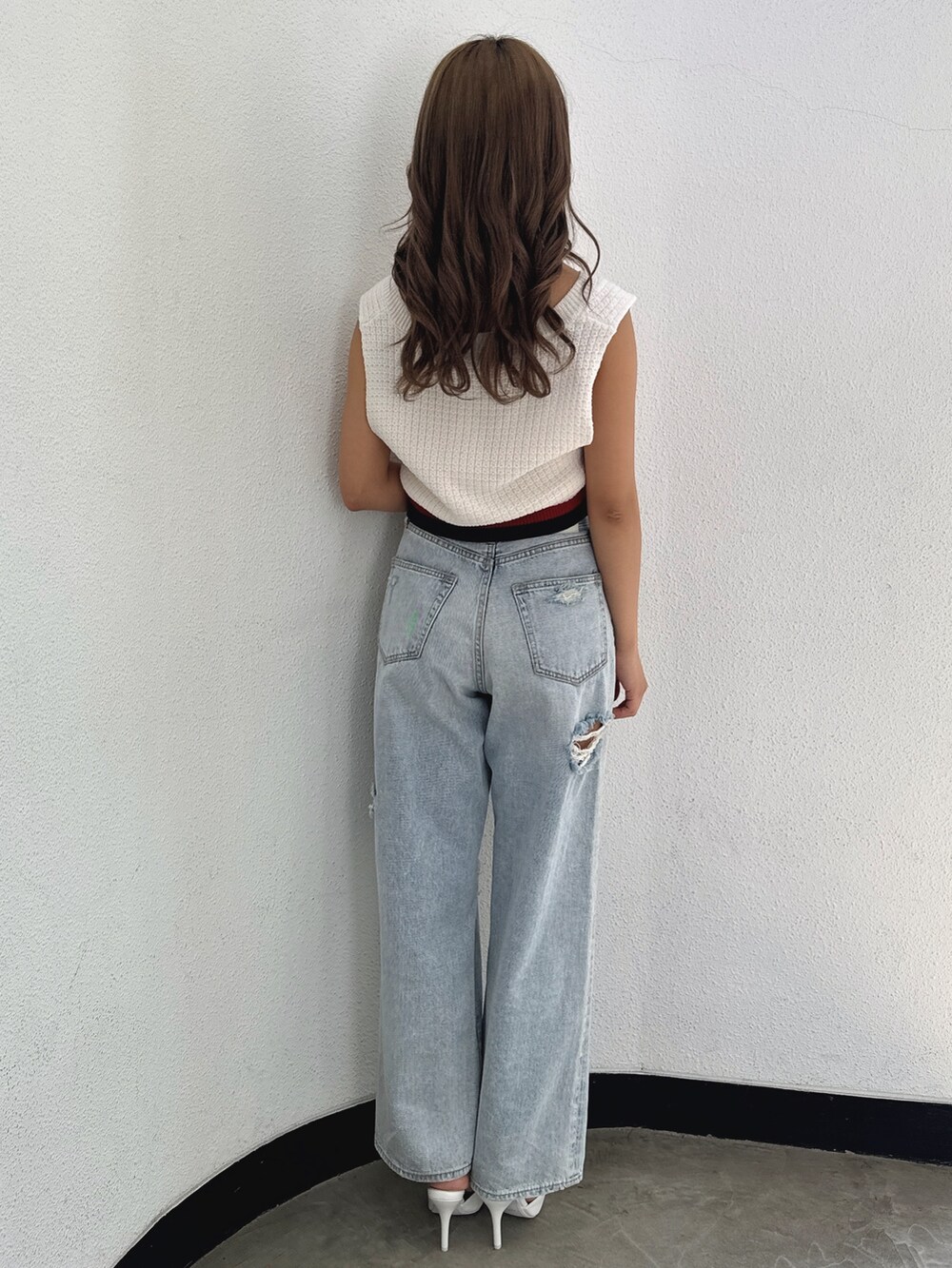 ホワイト系のニット/セーター、ブルー系のデニムパンツ、ホワイト系のパンプスを着用したレディースの春コーディネートの4枚目の写真