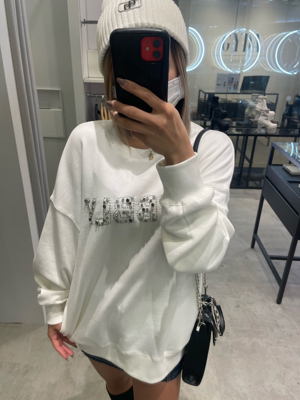 ホワイト系のスウェット、ブルー系のデニムスカート、ブラック系のショルダーバッグを着用したレディースの冬コーディネートの4枚目の写真