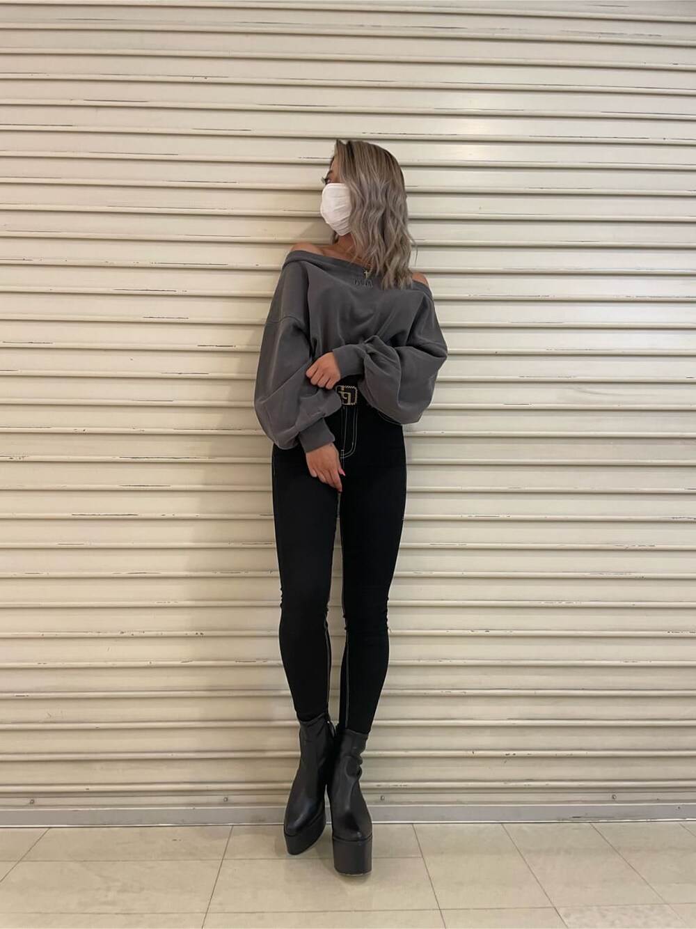 ブラック系のデニムパンツ、グレー系のスウェット、ブラック系のブーツを着用したレディースの秋コーディネートの2枚目の写真