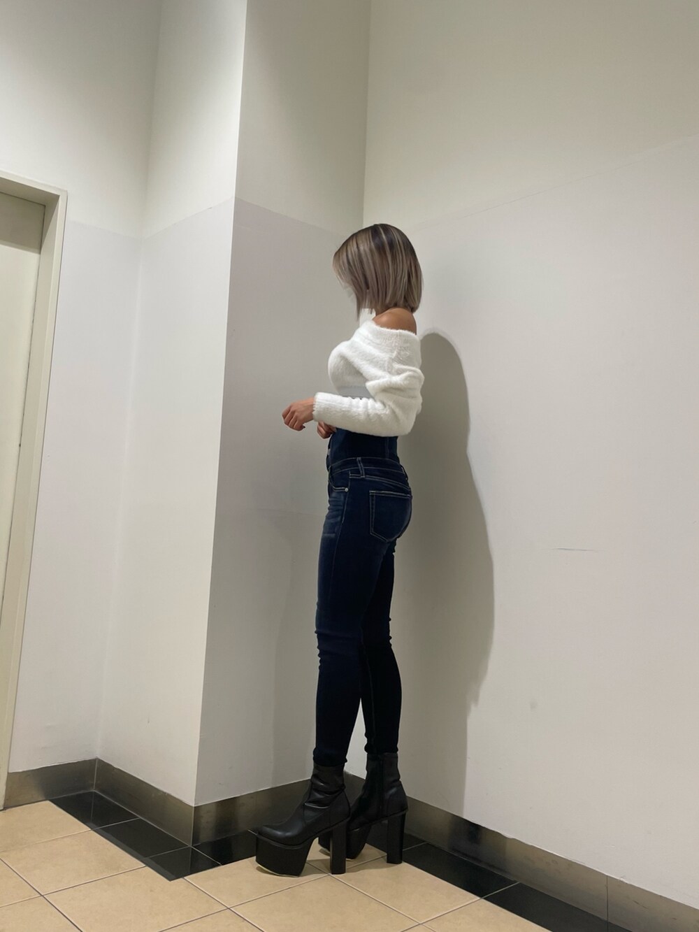 ブルー系のパンツ、ホワイト系のニット/セーター、ブラック系のブーツを着用したレディースの秋コーディネートの2枚目の写真