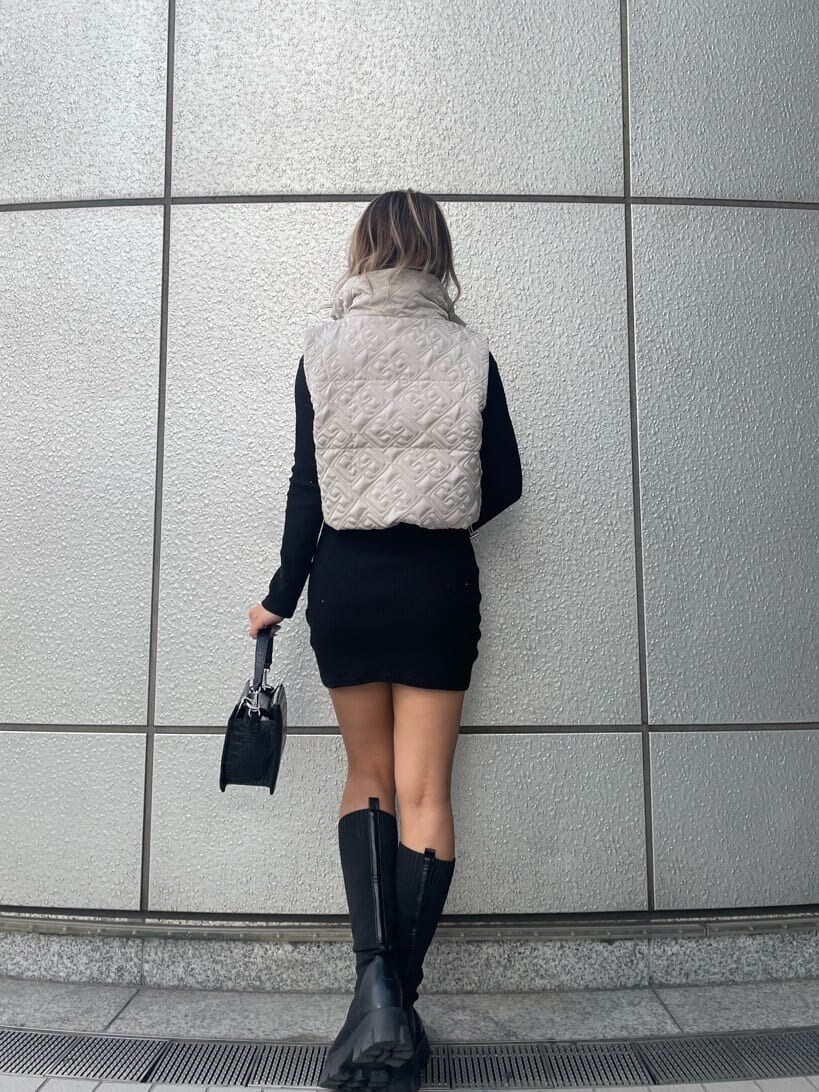 ブラック系のハンドバッグ、ブラック系のワンピース、ブラック系のブーツを着用したレディースの秋コーディネートの3枚目の写真