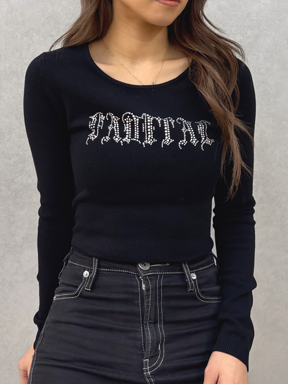 ブラック系のニット/セーター、ブラック系のデニムパンツ、ホワイト系のパンプスを着用したレディースの春コーディネートの6枚目の写真