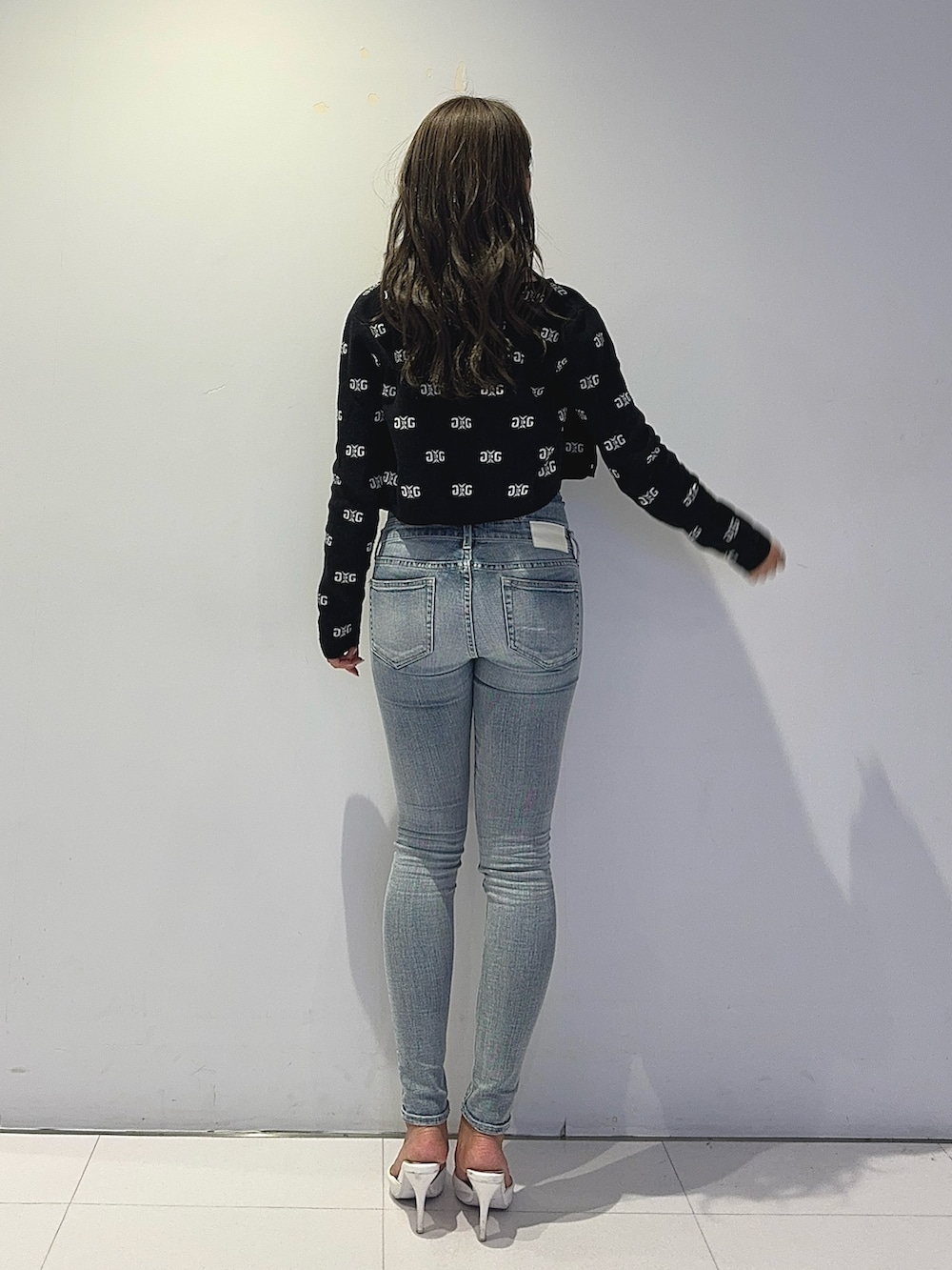 ブラック系のニット/セーター、ブルー系のデニムパンツ、ホワイト系のパンプスを着用したレディースの春コーディネートの5枚目の写真