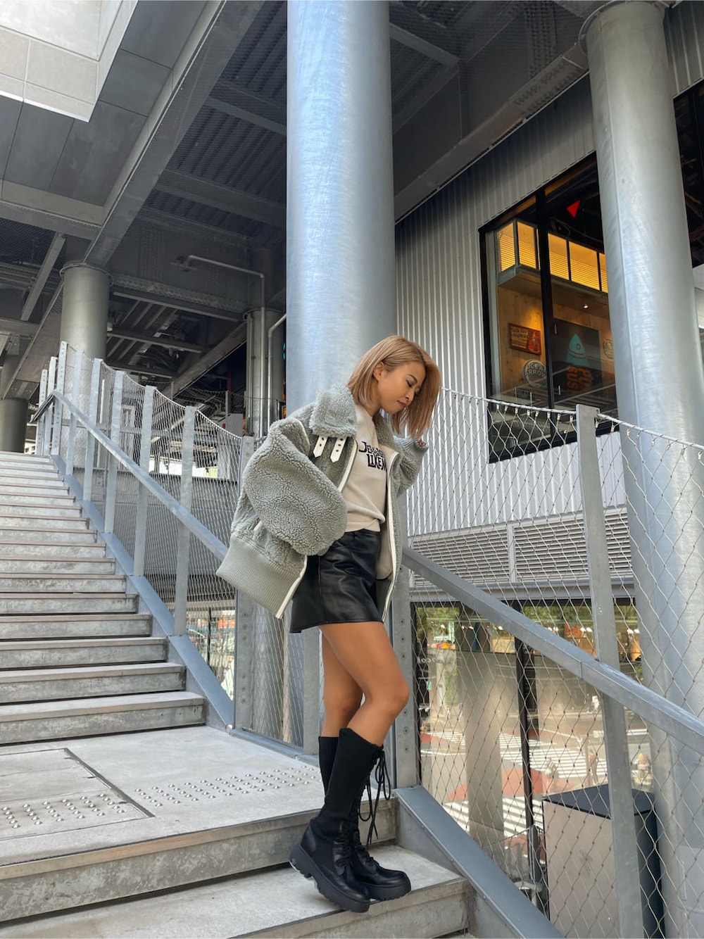 ブラック系のスカート、ホワイト系のニット/セーター、ブラック系のブーツを着用したレディースの秋コーディネートの2枚目の写真