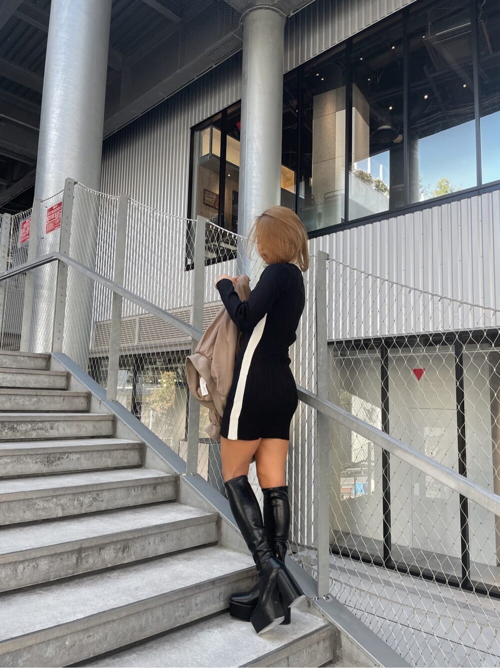 ベージュ系のMA-1、ブラック系のワンピース、ブラック系のブーツを着用したレディースの秋コーディネートの2枚目の写真