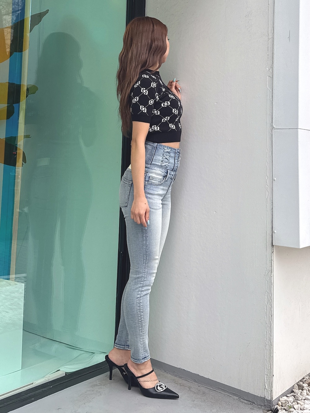 ブラック系のニット/セーター、ブルー系のデニムパンツ、ブラック系のパンプスを着用したレディースの春コーディネートの3枚目の写真