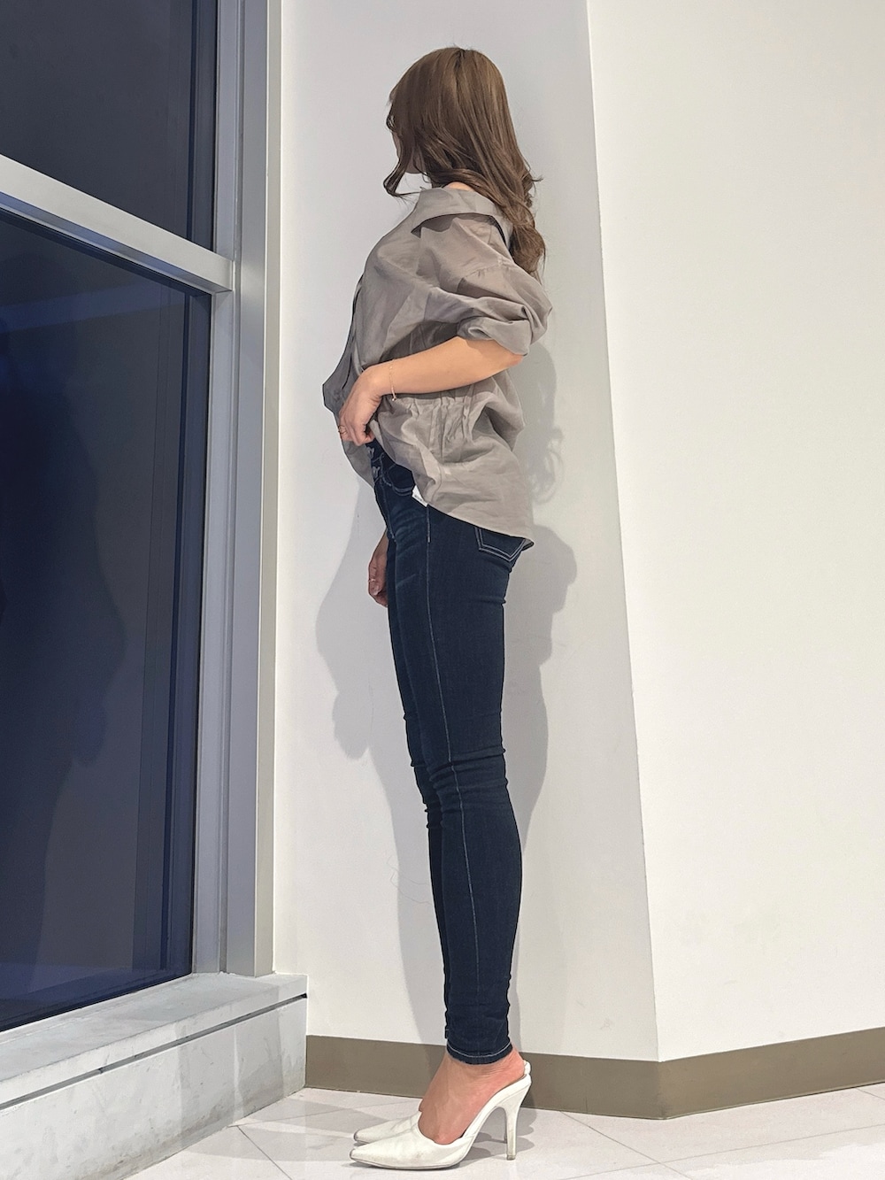 ベージュ系のシャツ/ブラウス、ブルー系のデニムパンツ、ホワイト系のパンプスを着用したレディースの春コーディネートの3枚目の写真