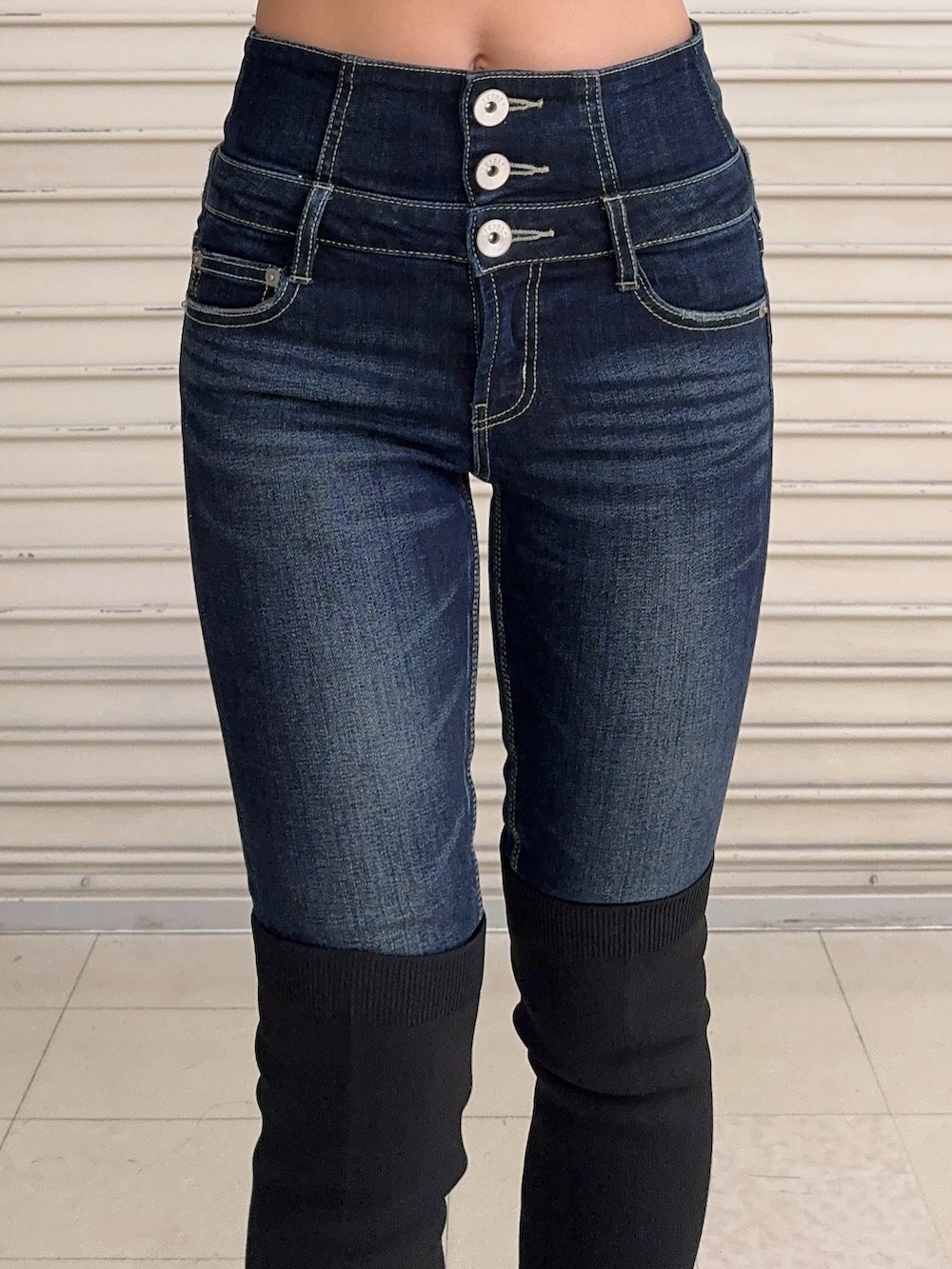 ブラック系のニット/セーター、ブルー系のデニムパンツ、ブラック系のブーツを着用したレディースの秋コーディネートの5枚目の写真