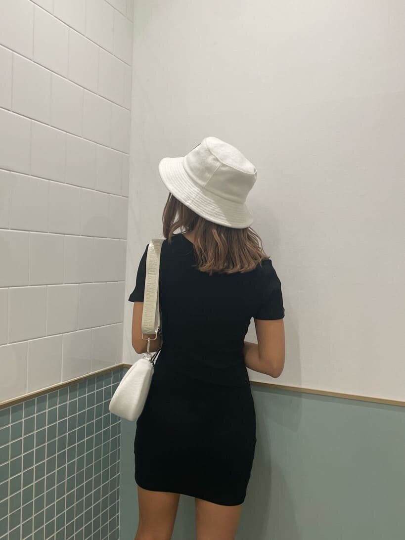 ブラック系のワンピース、ブラック系のサンダル、ホワイト系のハンドバッグを着用したレディースの春コーディネートの3枚目の写真