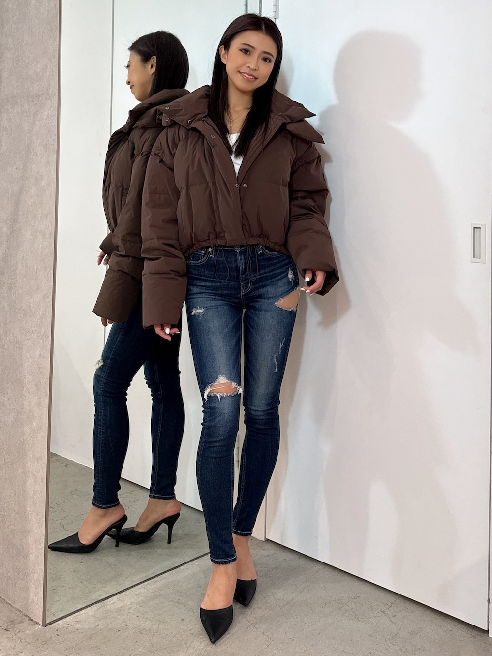 ホワイト系のTシャツ/カットソー、ブラウン系のダウンジャケット/コート、ブルー系のデニムパンツを着用したレディースの秋コーディネートの2枚目の写真