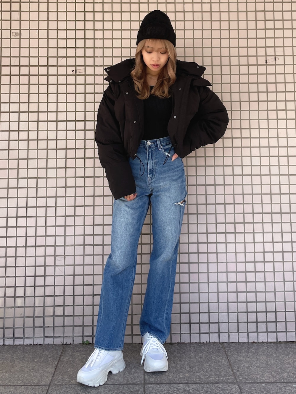 ホワイト系のスニーカー、ブルー系のデニムパンツ、ブラック系のニット/セーターを着用したレディースの冬コーディネートの2枚目の写真