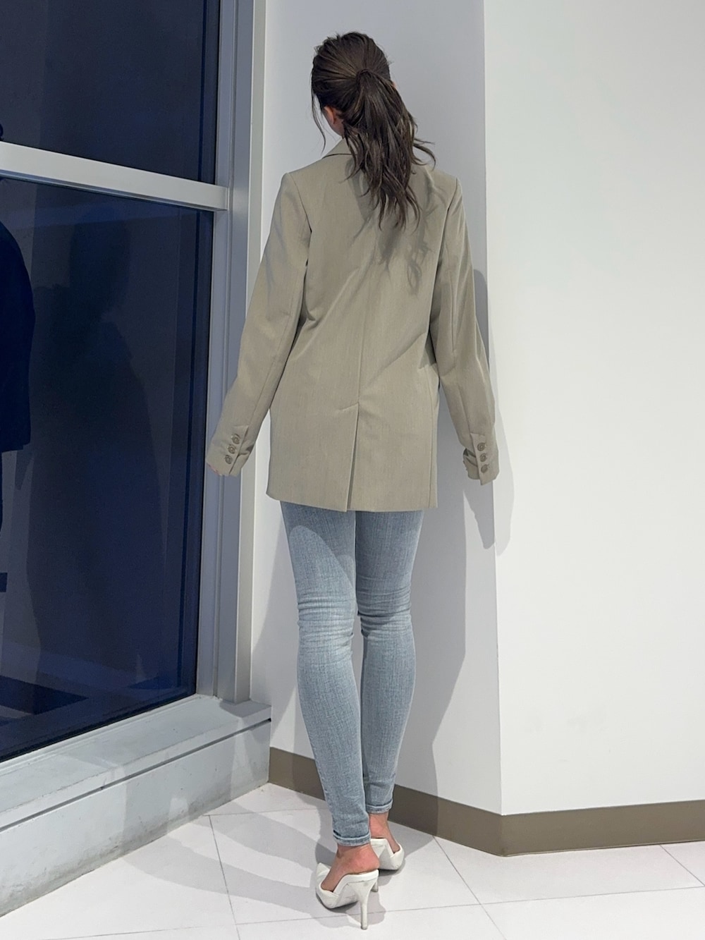 ベージュ系のテーラードジャケット、ブルー系のデニムパンツ、ホワイト系のパンプスを着用したレディースの春コーディネートの5枚目の写真