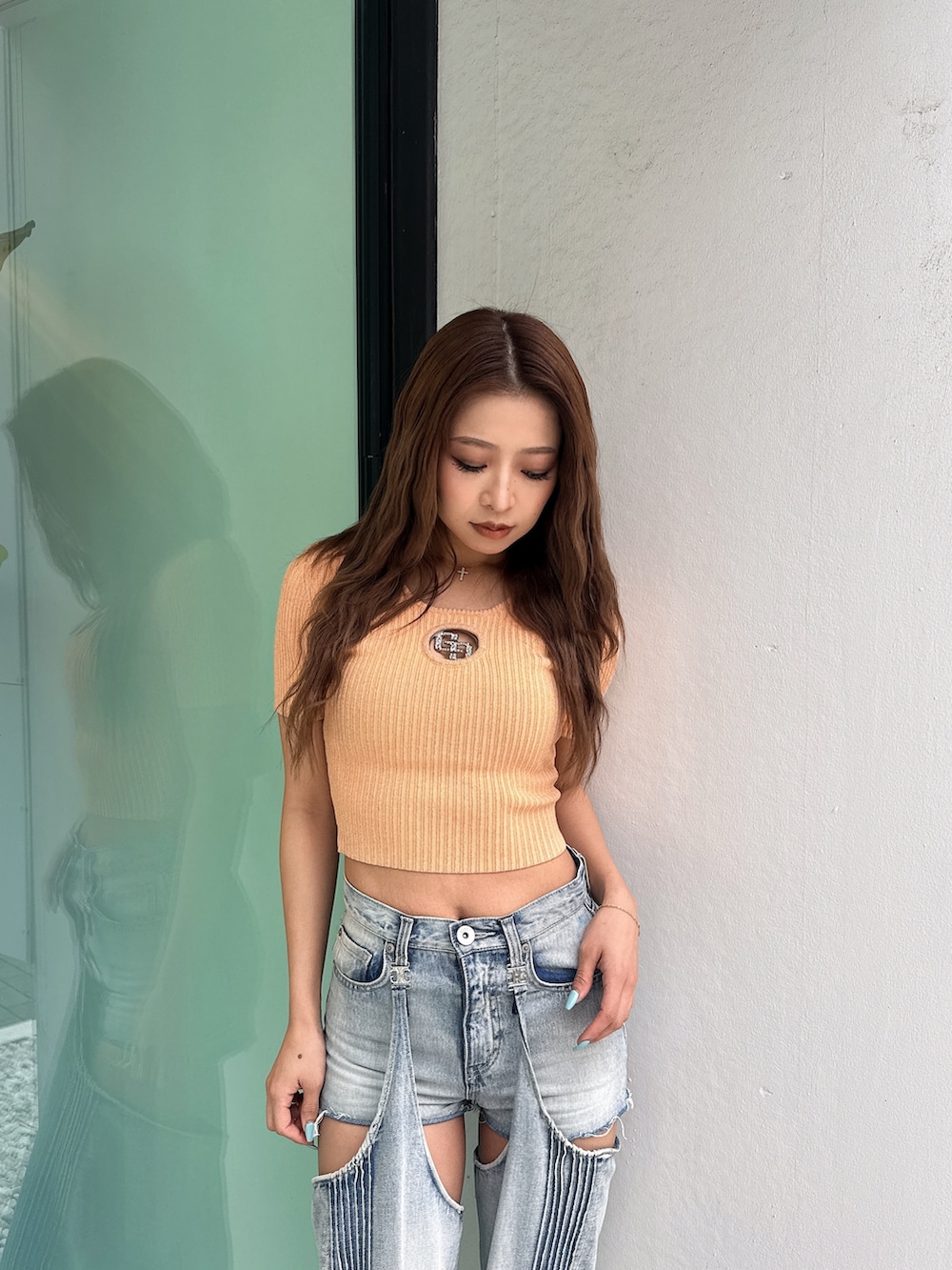 オレンジ系のニット/セーター、ブルー系のデニムパンツ、ホワイト系のパンプスを着用したレディースの春コーディネートの6枚目の写真