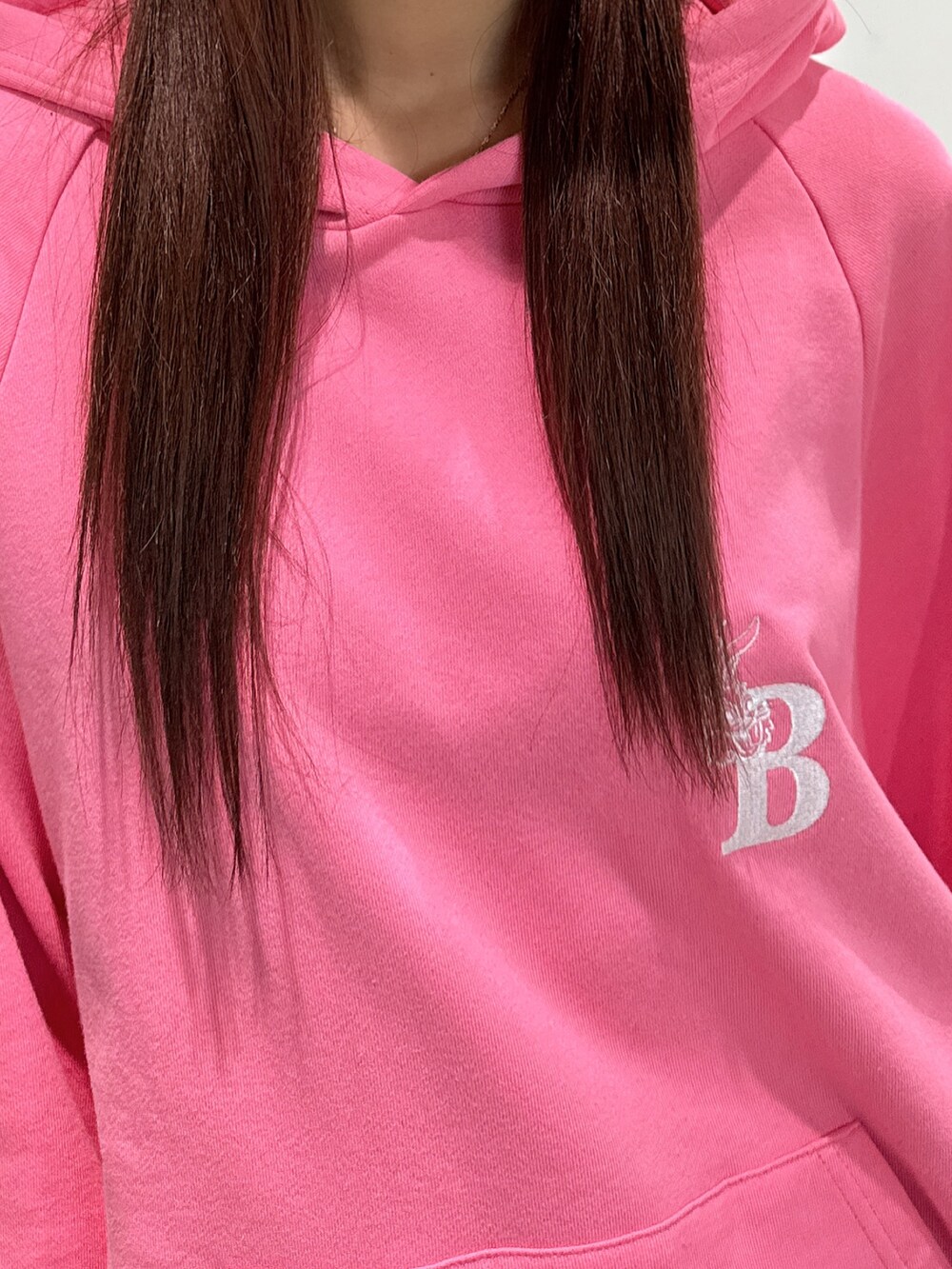 ピンク系のパーカー、ブラック系のショルダーバッグ、ブラック系のブーツを着用したレディースの冬コーディネートの4枚目の写真