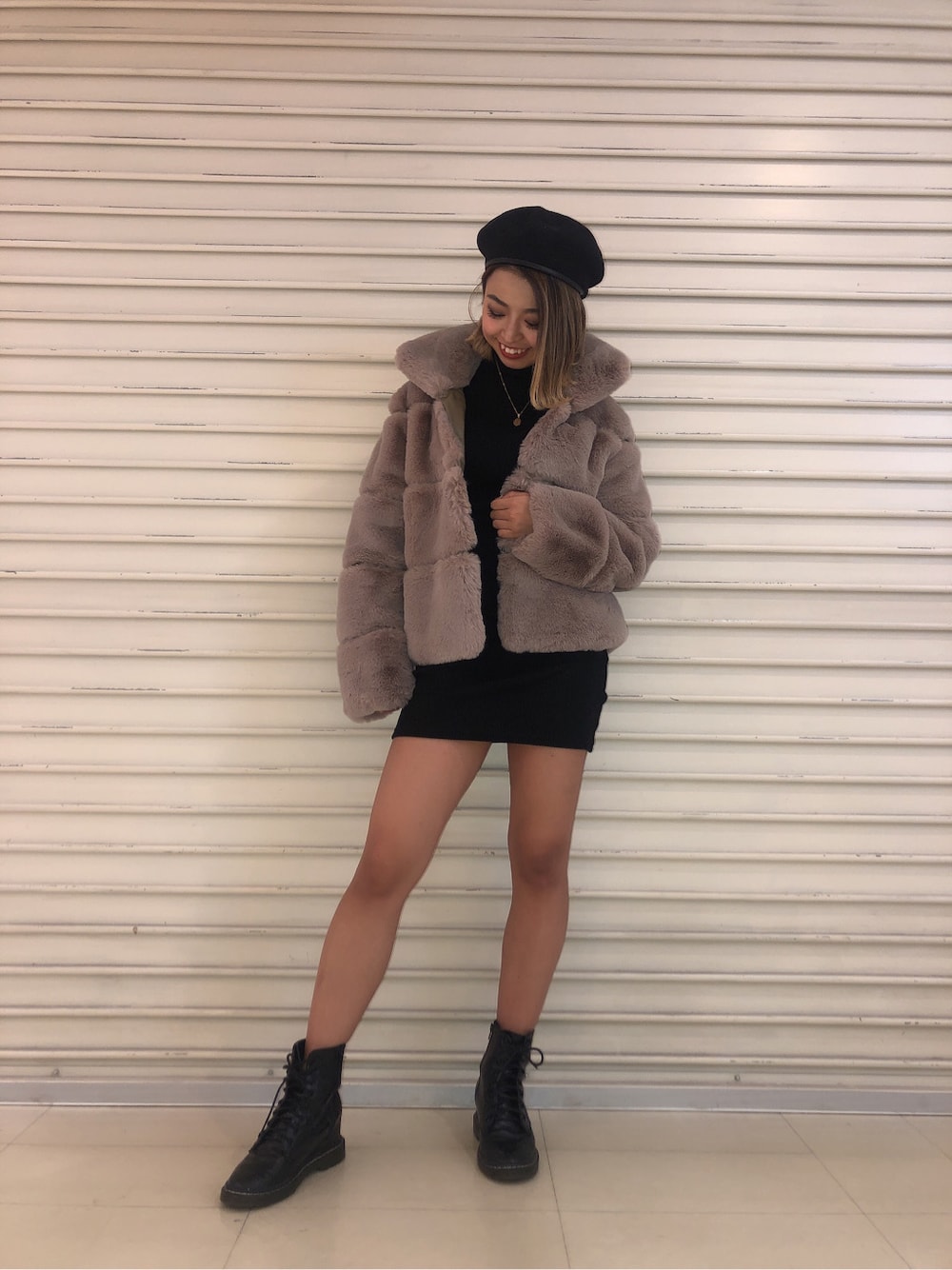 ベージュ系のムートンコート、ブラック系のワンピースを着用したレディースの冬コーディネートの2枚目の写真