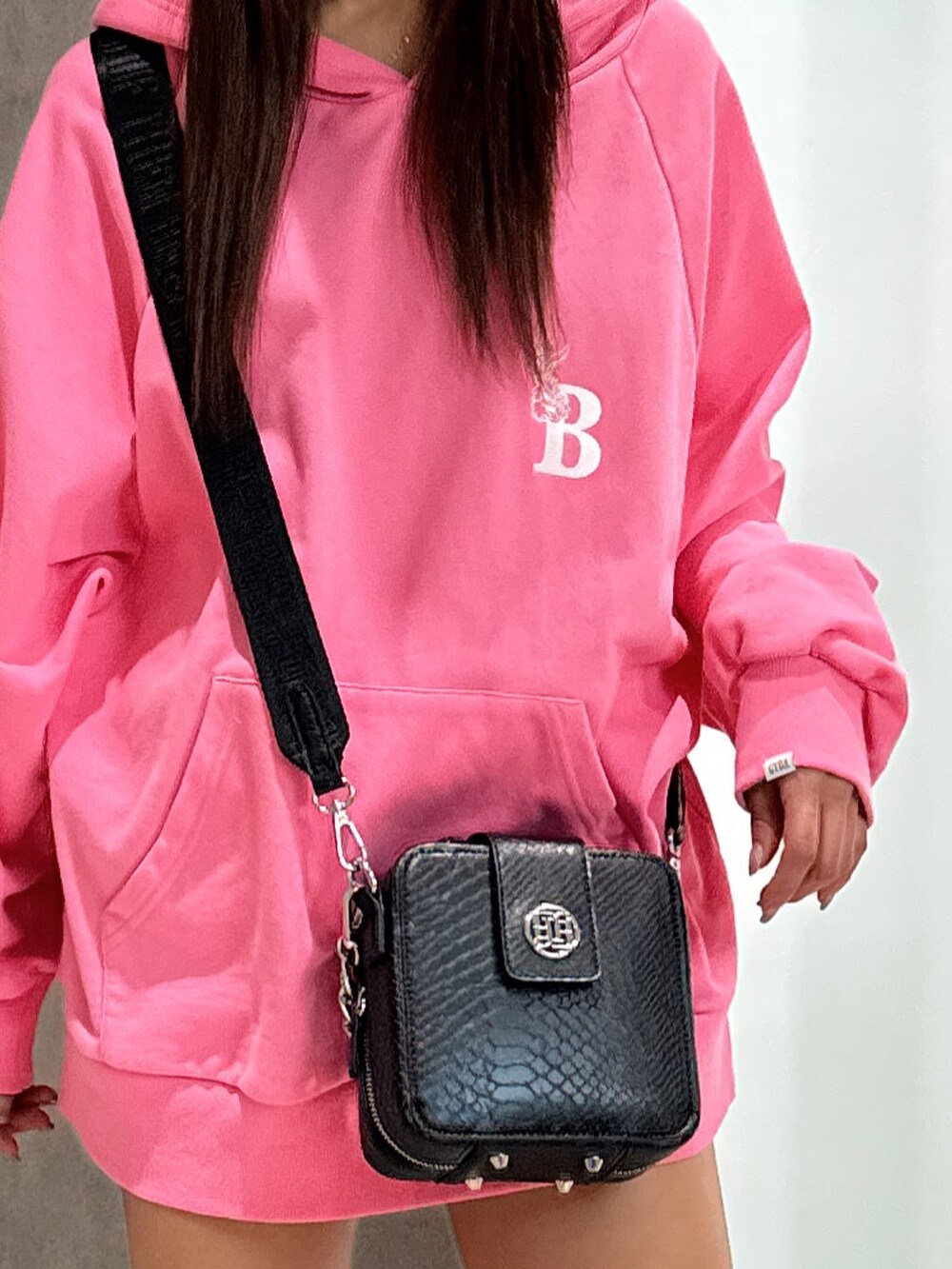 ピンク系のパーカー、ブラック系のショルダーバッグ、ブラック系のブーツを着用したレディースの冬コーディネートの5枚目の写真