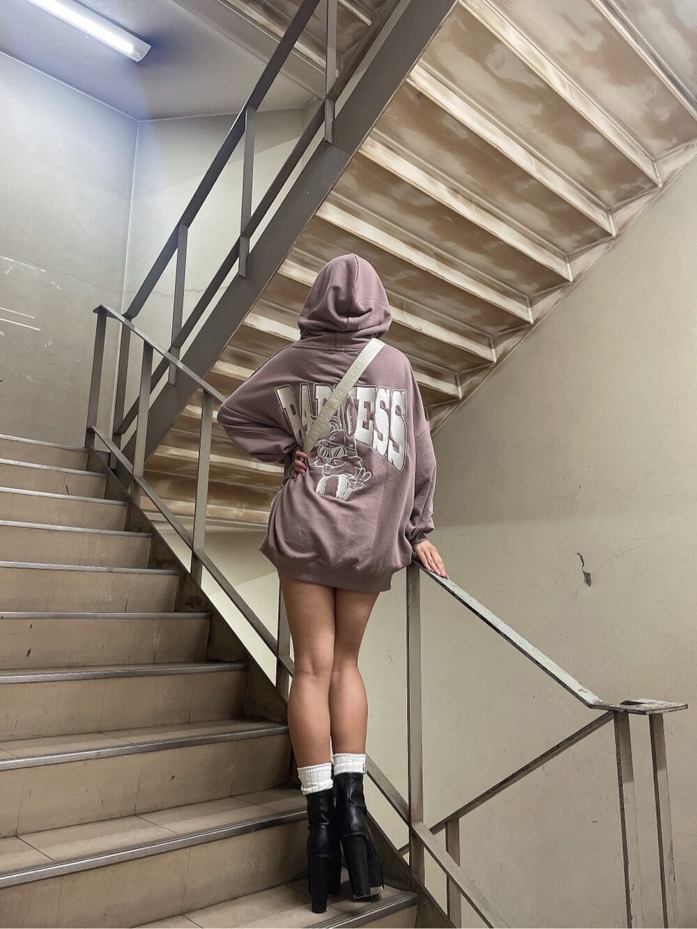 ブラック系のブーツ、ホワイト系のショルダーバッグ、ピンク系のパーカーを着用したレディースの秋コーディネートの4枚目の写真