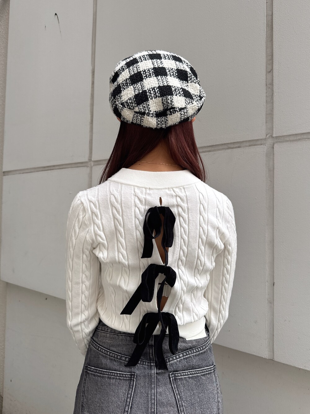 ホワイト系のニット/セーター、ブラック系のデニムスカート、その他のバックパック/リュックを着用したレディースの秋コーディネートの5枚目の写真