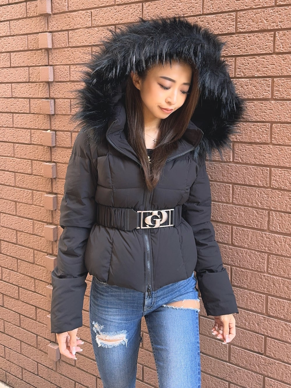 ブラック系のダウンジャケット/コート、ブラック系のニット/セーター、ブルー系のデニムパンツを着用したレディースの秋コーディネートの6枚目の写真