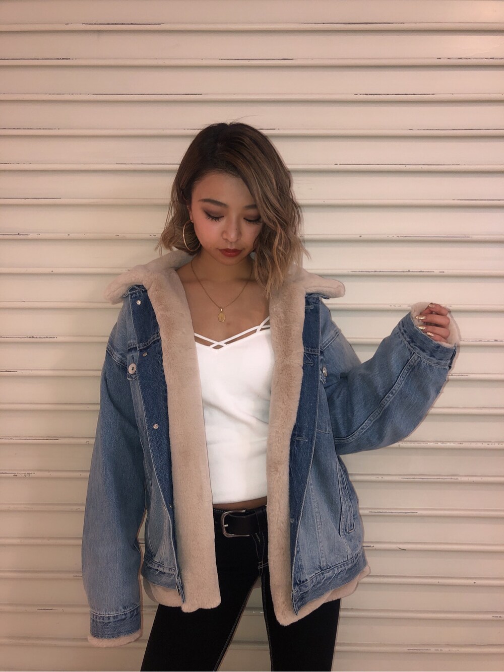 ブラック系のデニムパンツ、ホワイト系のキャミソール、ベージュ系のテーラードジャケットを着用したレディースの秋コーディネートの2枚目の写真