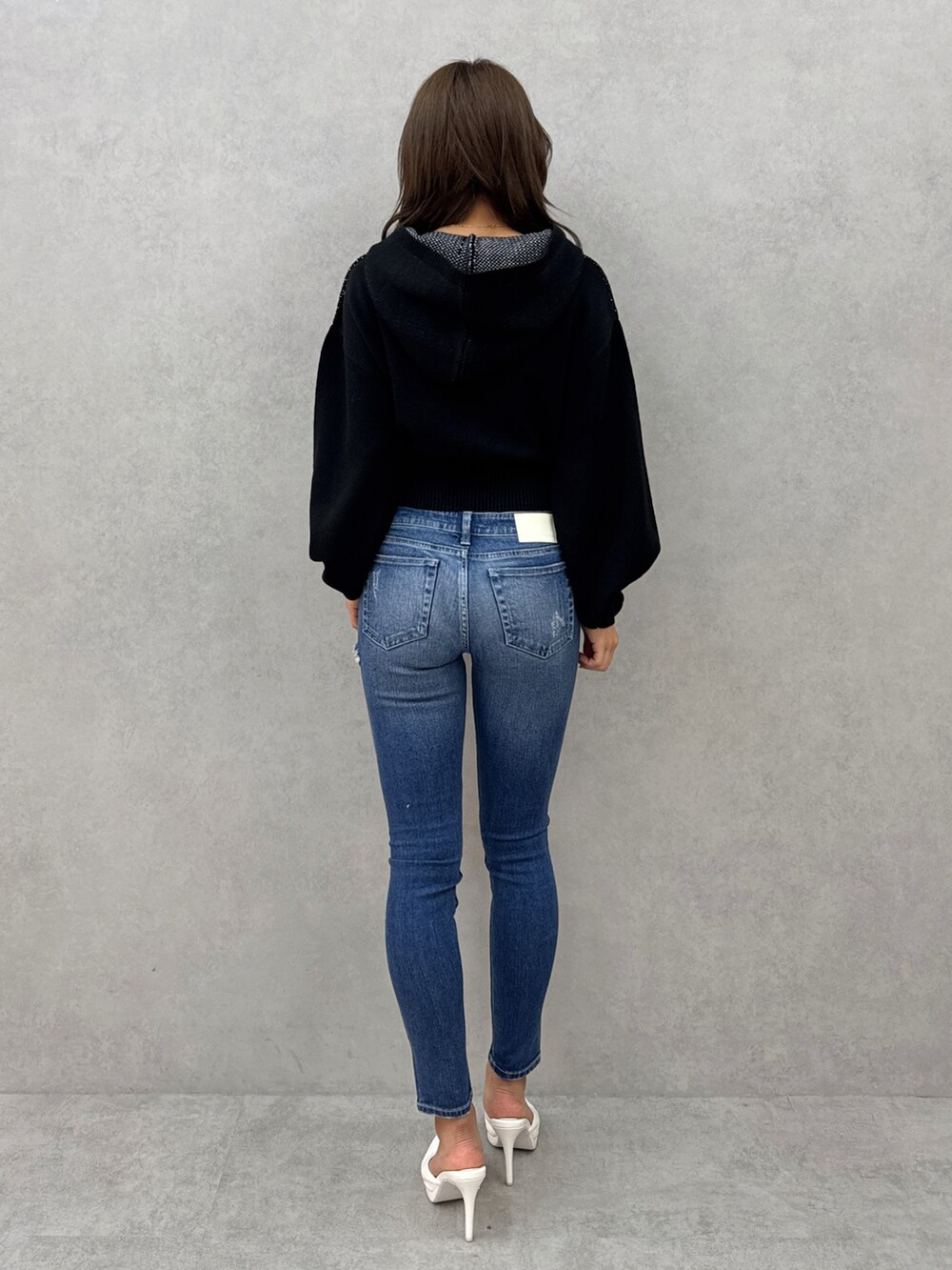 ブラック系のニット/セーター、ブルー系のデニムパンツ、ホワイト系のパンプスを着用したレディースの冬コーディネートの3枚目の写真