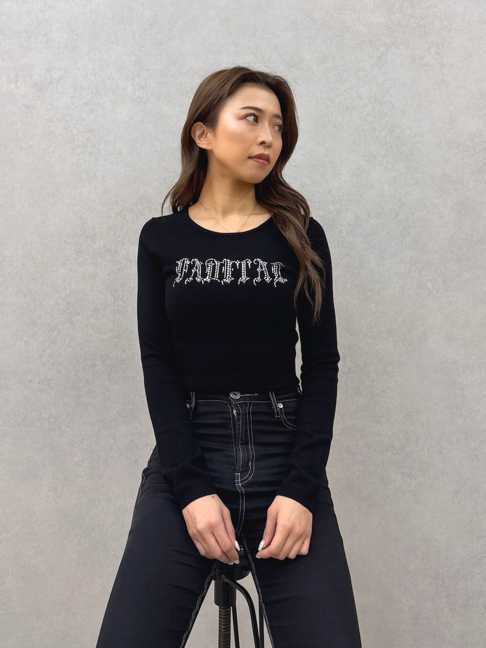 ブラック系のニット/セーター、ブラック系のデニムパンツ、ホワイト系のパンプスを着用したレディースの春コーディネートの5枚目の写真