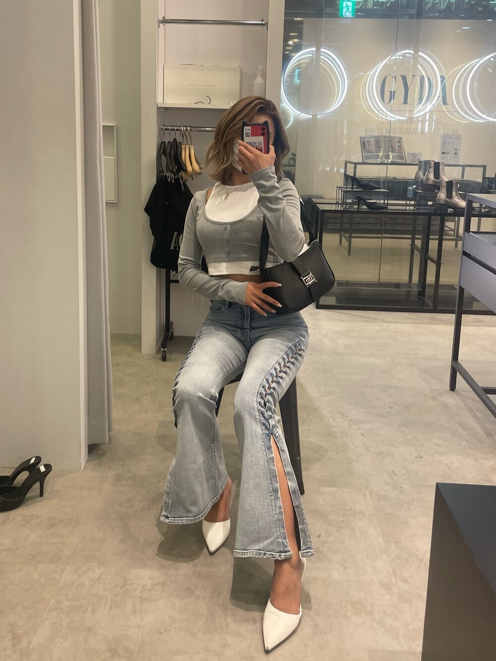 グレー系のTシャツ/カットソー、ブルー系のデニムパンツ、ブラック系のハンドバッグを着用したレディースの冬コーディネートの2枚目の写真