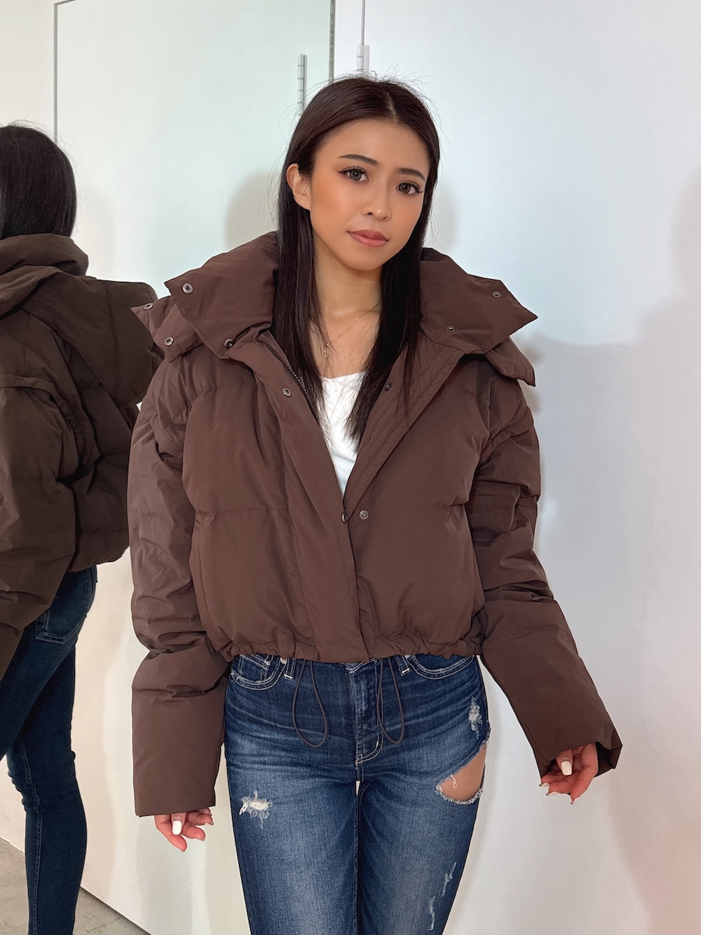 ホワイト系のTシャツ/カットソー、ブラウン系のダウンジャケット/コート、ブルー系のデニムパンツを着用したレディースの秋コーディネートの5枚目の写真