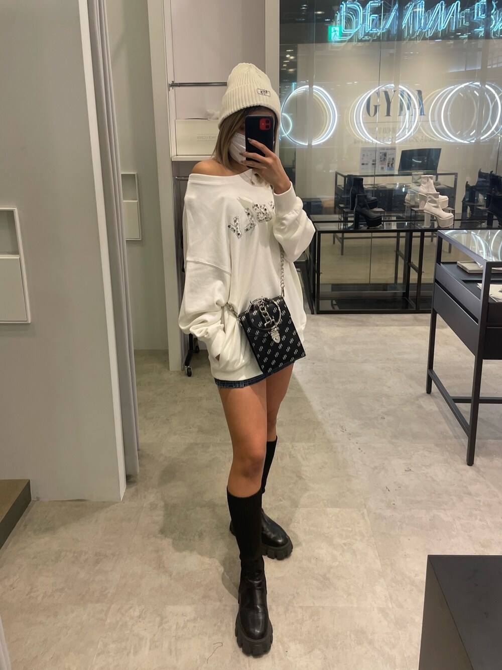 ホワイト系のスウェット、ブルー系のデニムスカート、ブラック系のショルダーバッグを着用したレディースの冬コーディネートの2枚目の写真