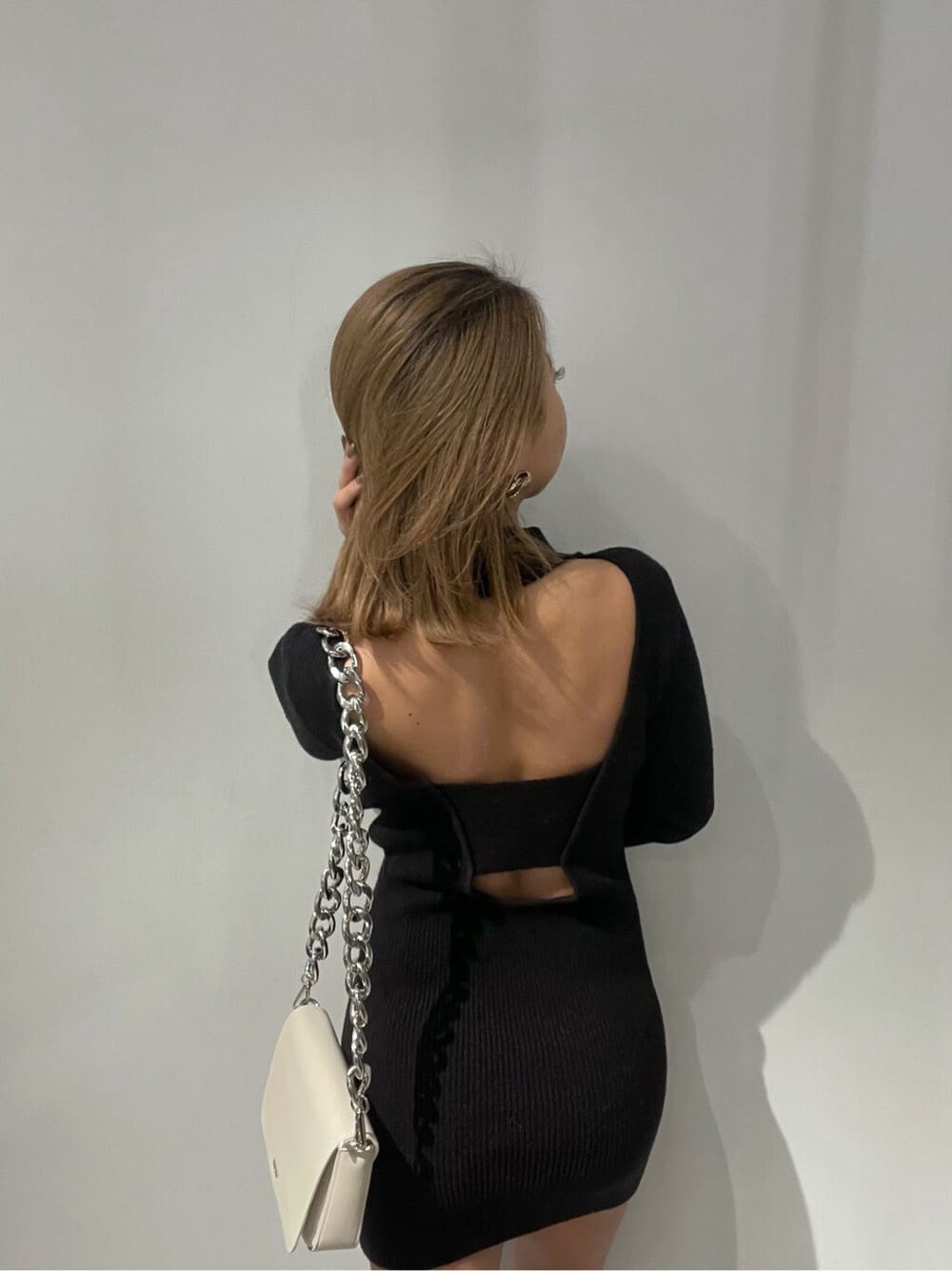 ホワイト系のショルダーバッグ、ブラック系のワンピースを着用したレディースの冬コーディネートの4枚目の写真