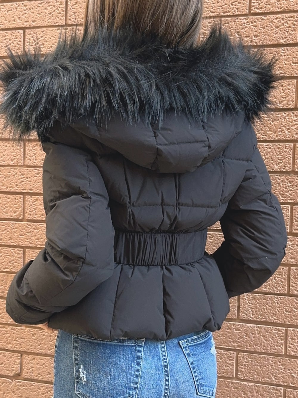 ブラック系のダウンジャケット/コート、ブラック系のニット/セーター、ブルー系のデニムパンツを着用したレディースの秋コーディネートの10枚目の写真