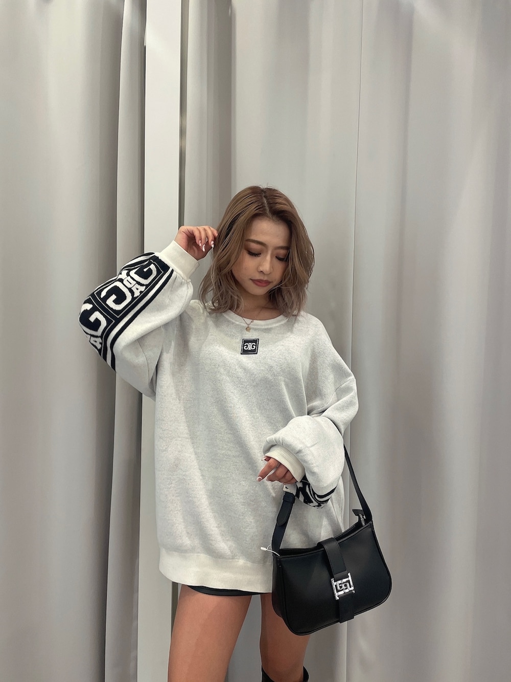 ブラック系のブーツ、ブラック系のハンドバッグ、ホワイト系のニット/セーターを着用したレディースの冬コーディネートの6枚目の写真