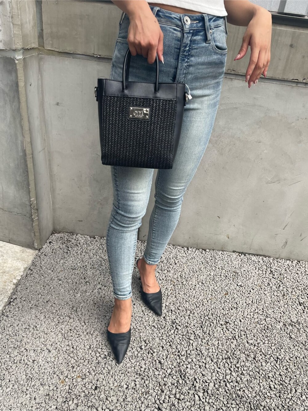 ホワイト系のパンプス、ブラック系のハンドバッグ、ブルー系のデニムパンツを着用したレディースの夏コーディネートの7枚目の写真