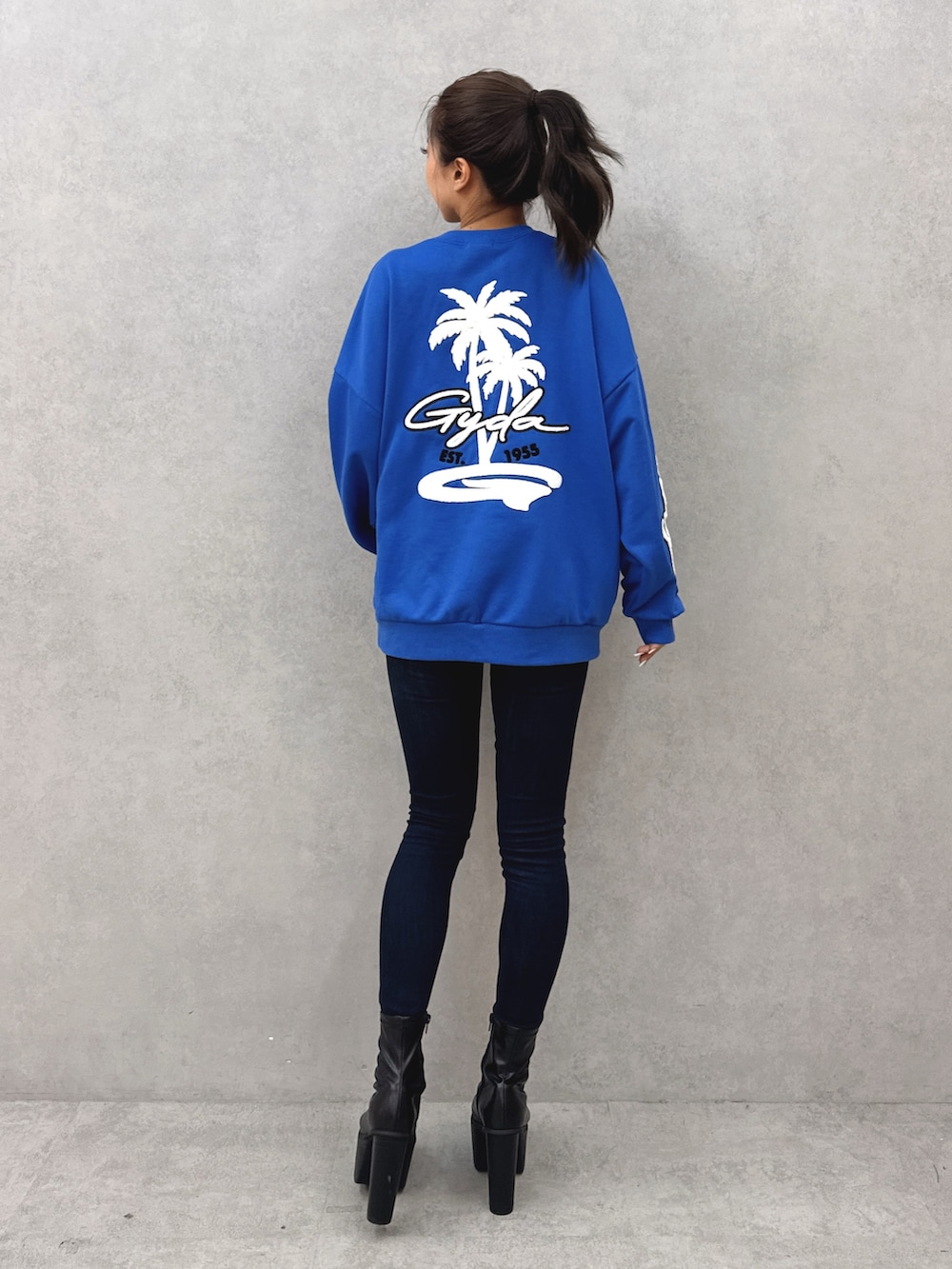 ブルー系のスウェット、ブルー系のデニムパンツ、ブラック系のブーツを着用したレディースの秋コーディネートの3枚目の写真