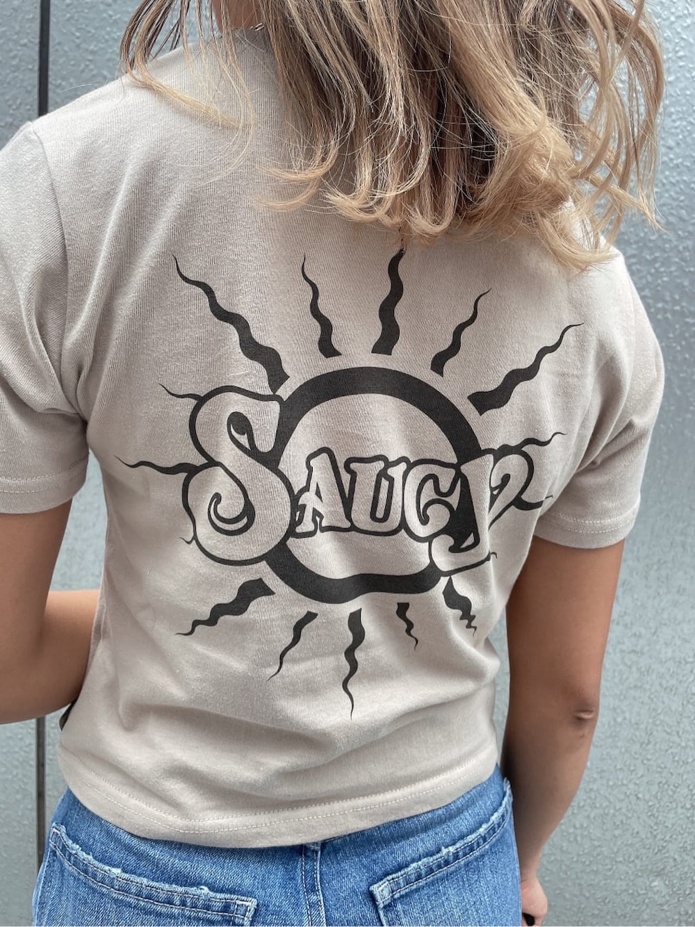 ブルー系のデニムパンツ、ホワイト系のハンドバッグ、ベージュ系のTシャツ/カットソーを着用したレディースの夏コーディネートの6枚目の写真