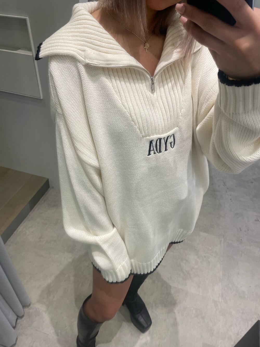 ホワイト系のニット/セーター、ブラック系のスカート、ブラック系のブーツを着用したレディースの冬コーディネートの3枚目の写真