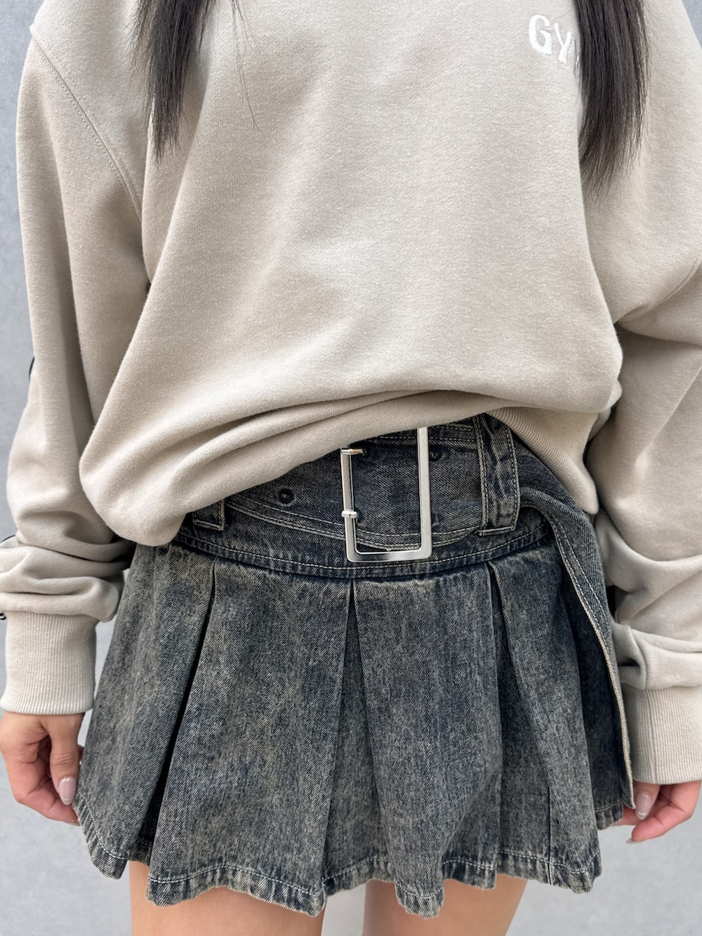 ベージュ系のスウェット、ブルー系のデニムスカート、ブラック系のブーツを着用したレディースの春コーディネートの6枚目の写真