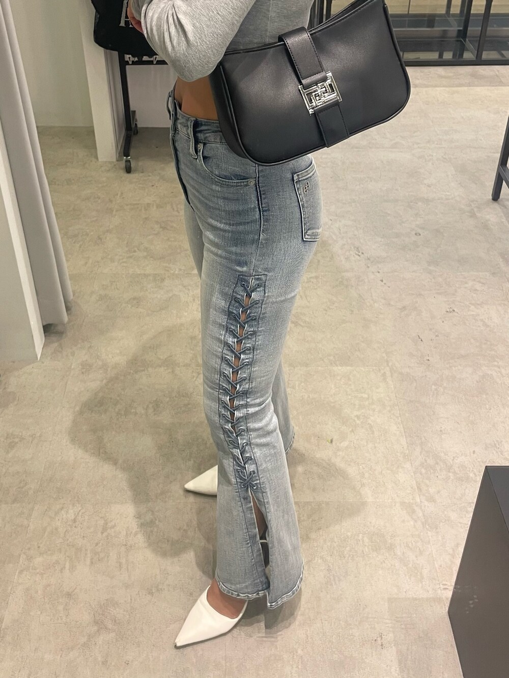 グレー系のTシャツ/カットソー、ブルー系のデニムパンツ、ブラック系のハンドバッグを着用したレディースの冬コーディネートの6枚目の写真